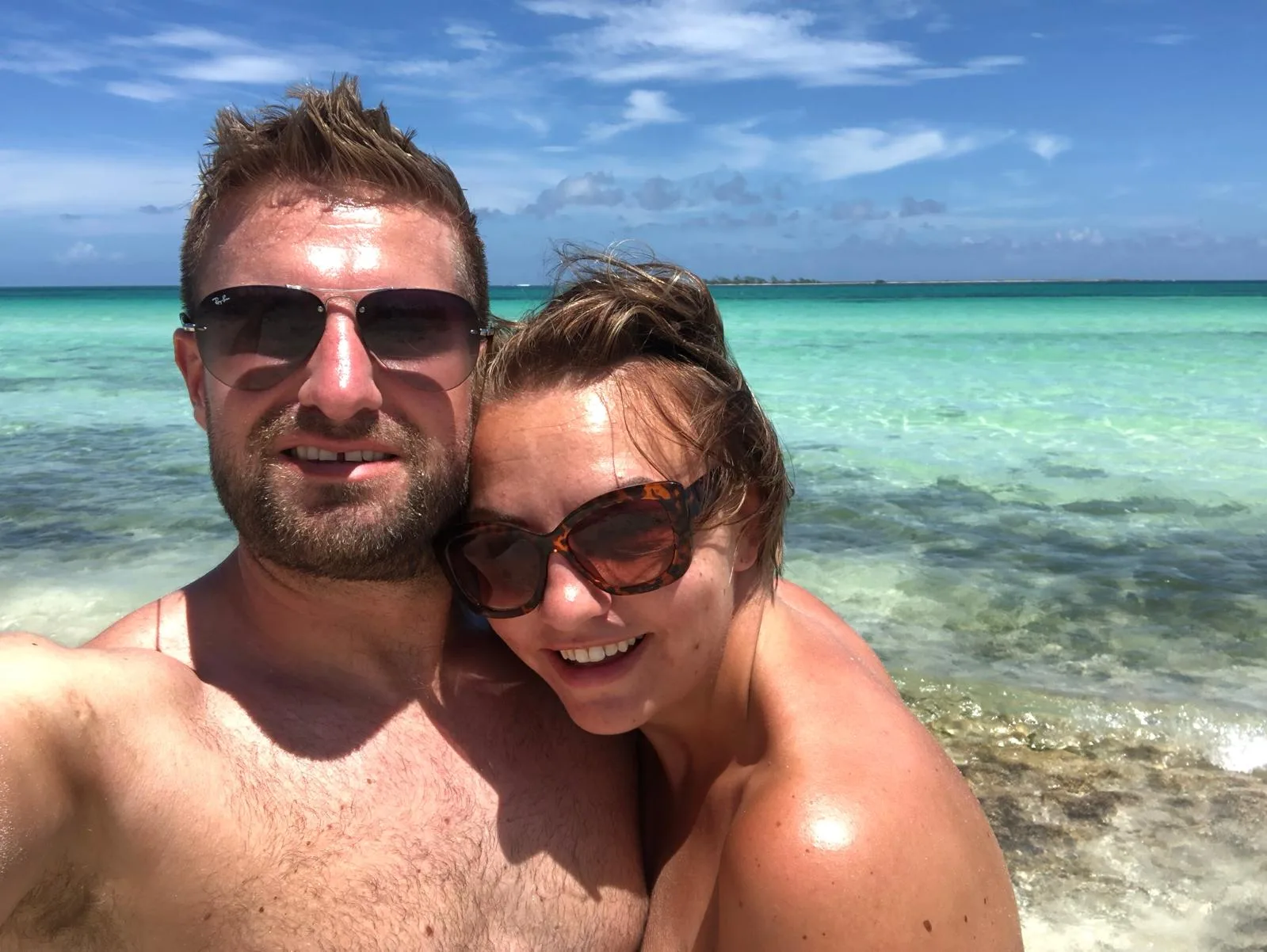 Sam and her husband taking a selfie in shallow turquoise water in Cuba