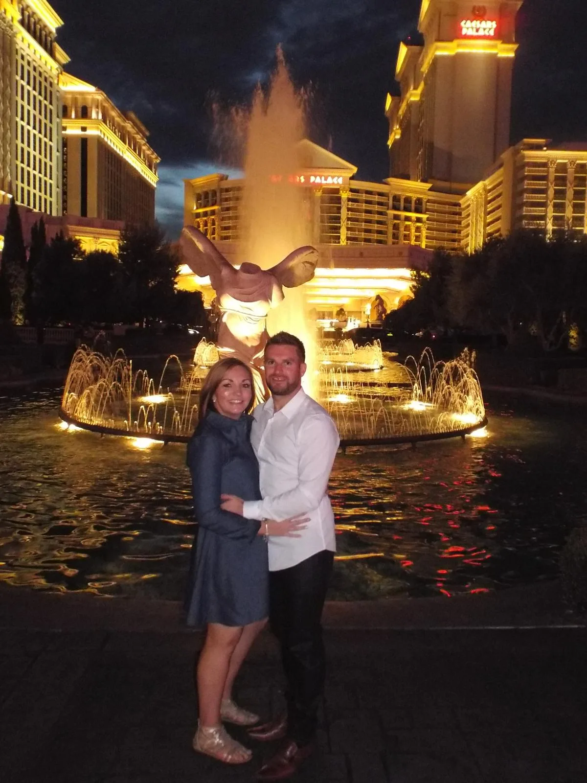 Sam and her husband in front of the Bellagio fountains in Las Vegas at night